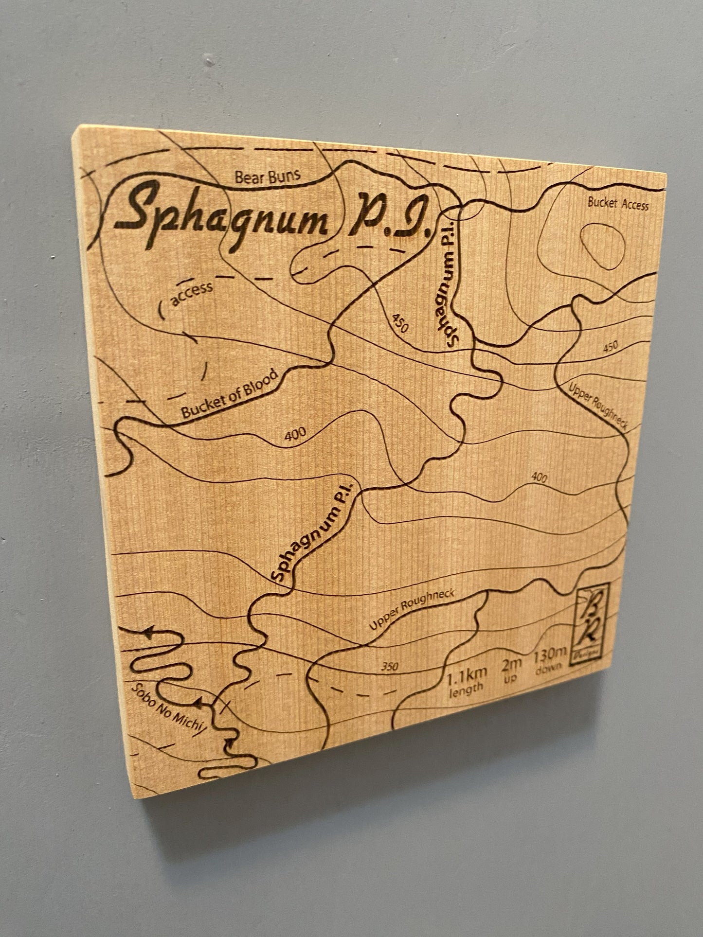 A wooden map tile featuring a detailed trail map of Sphagnum P.I. in the Cumberland mountain bike trails.