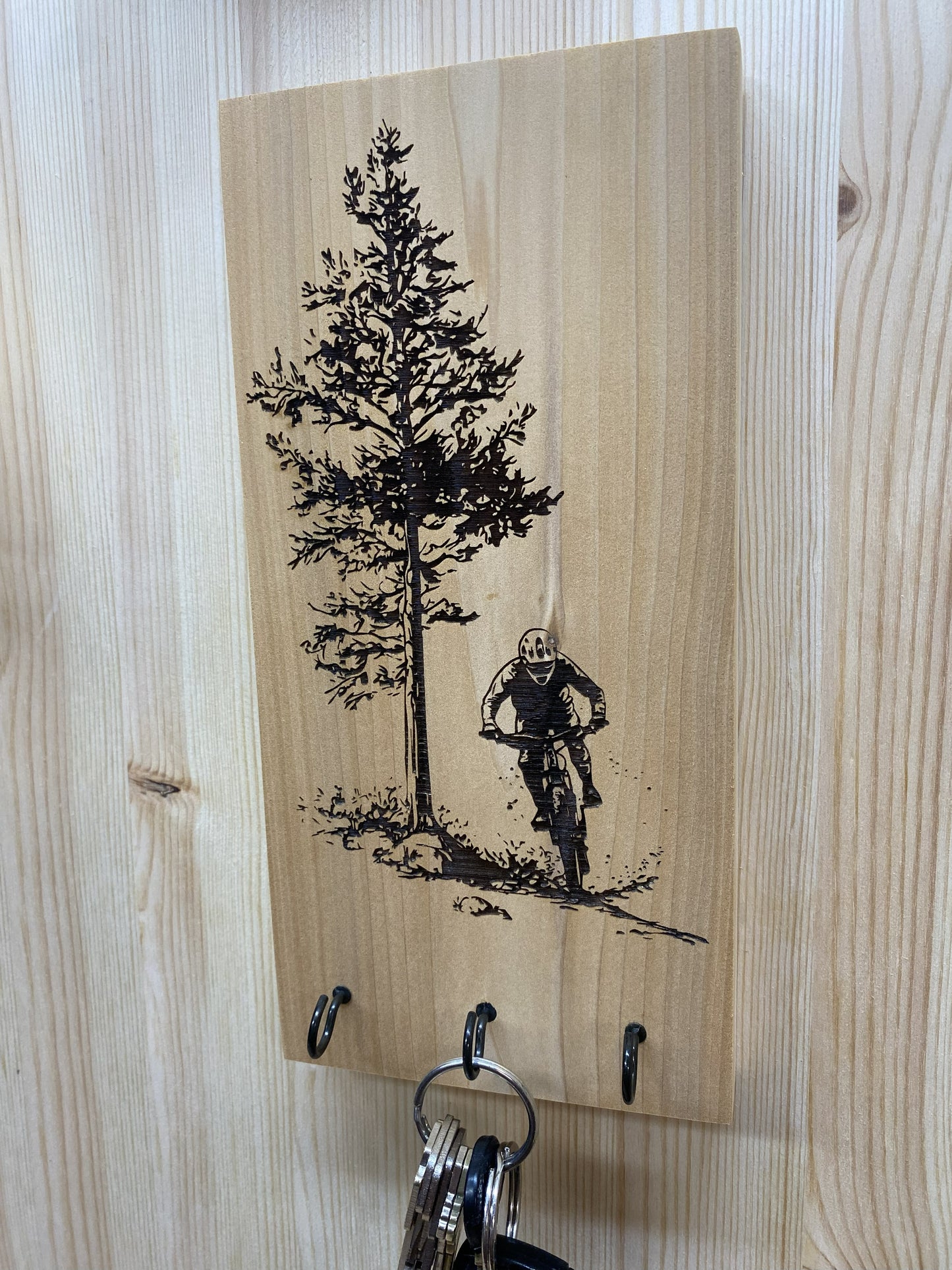 Wooden key holder with engraved tree and mountain biker design.