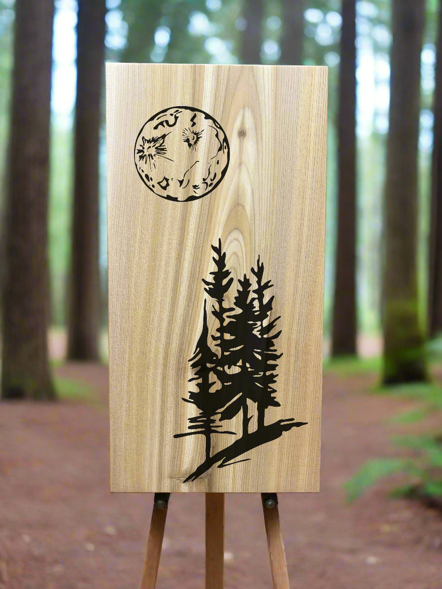 A wood wall tile with a moon and tree design, displayed in a forest.