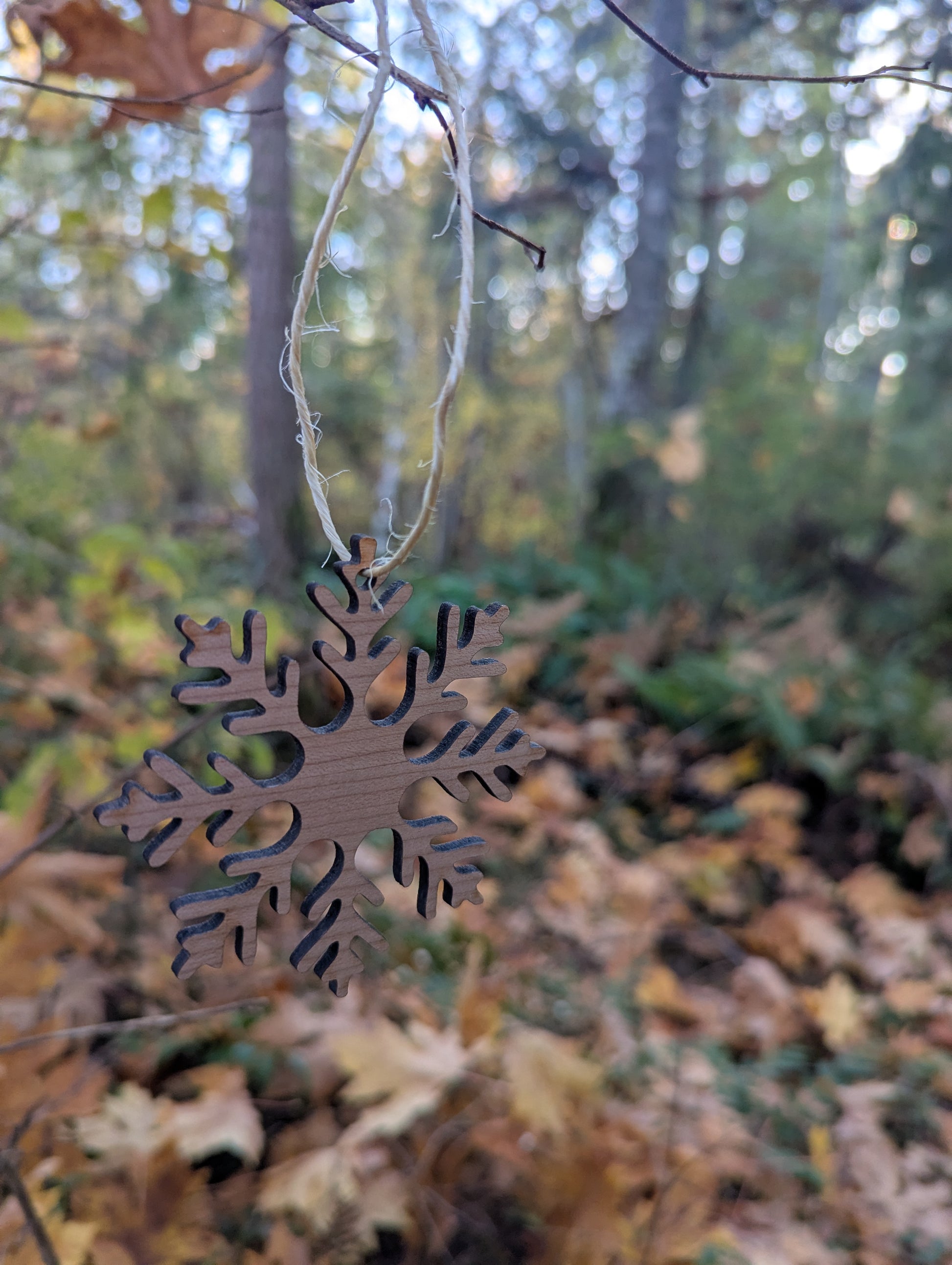 Handcrafted Wooden Snowflake Ornament hanging in a BC forest, ideal rustic Christmas decor.