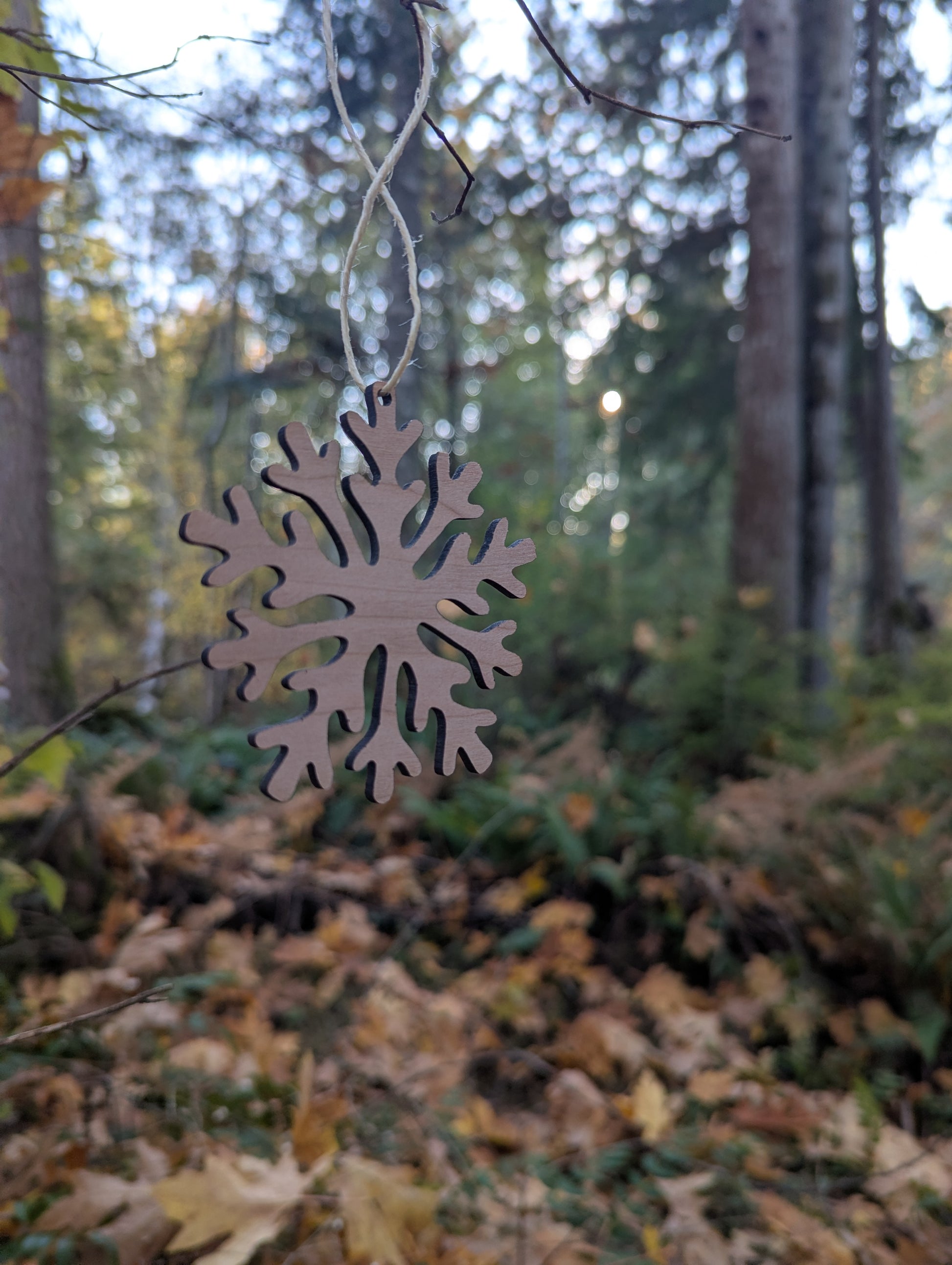 Handcrafted Wooden Snowflake Ornament hanging in a BC forest, ideal rustic Christmas decor.
